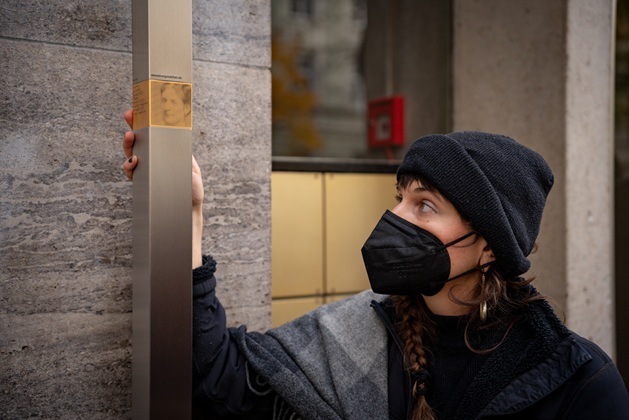 Eine Angehörige bringt das Erinnerungszeichen für Flora Fromm an